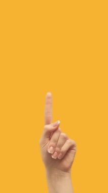 Vertical video. Recommending sign. Special offer. Female hand finger pointing up demonstrating blank area on orange empty space commercial background loop.
