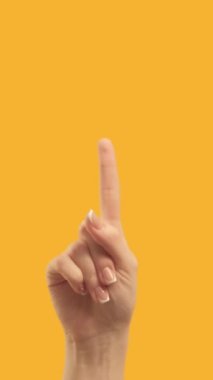 Vertical video. Hand pointing up. Commercial background. Female index finger showing demonstrating announcement on orange empty space.