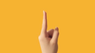 Finger pointing up. Attention gesture. Female hand showing recommending something above on orange empty space advertising background.