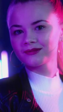 Neon ışıklı parti. Mutlu kadın. Dans eğlencesi. Gece kulübünde mor ışıklarla dans eden at kuyruklu güzel bayan. Dikey video.