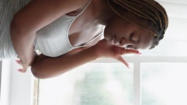 Vertical video. Morning headache. Friend care. Compassion sympathy. Supportive woman bringing glass of water to female roommate suffering from migraine at light white window.