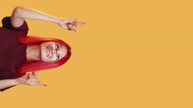Vertical video. Special offer. Look here. Great opportunity. Happy excited woman pointing up presenting something invisible on yellow copy space commercial background.