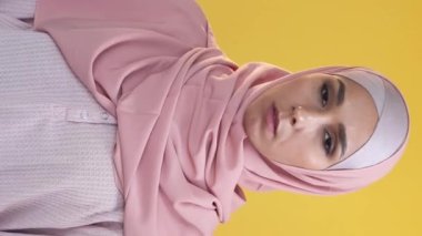 Vertical video. Enough gesture. Refusal no. Female protest. Portrait of disturbed skeptic woman in hijab warning with strict nope crossed hands X sign on orange.