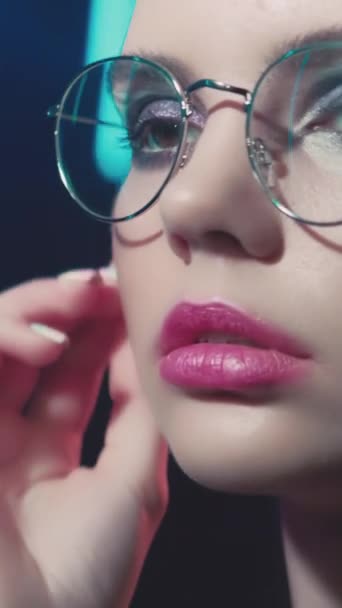 垂直录像 90年代时尚 眼镜模型 2000年代漂亮的样子 浅蓝色霓虹灯下身穿圆形镜框眼镜的少女面容 — 图库视频影像