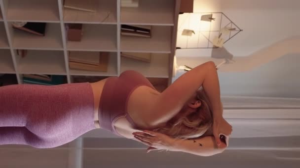 垂直ビデオ 三脚が伸びてる 現役女性 健康的なライフスタイル スポーティな女性でスポーツウェアのトレーニング腕の筋肉で軽い部屋のインテリア — ストック動画