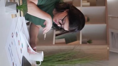 Vertical video. Statistics research. Data analysis. Financial review. Busy serious woman employee working with graphs charts at home office workplace.