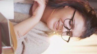 Vertical video. Reading hobby. Weekend leisure. Home rest. Relaxed curious smart woman in glasses enjoying favorite interesting book.