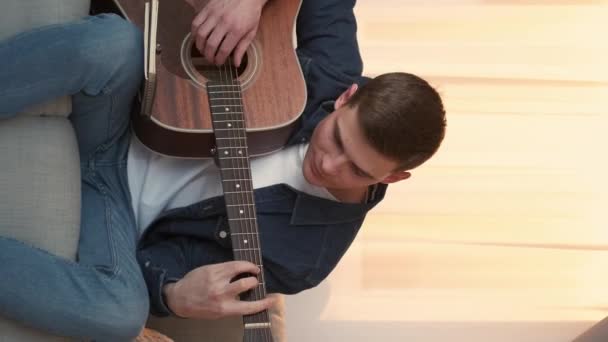 垂直录像 吉他的练习 在家学习 心烦意乱的人坐在沙发灯室里用弦乐器弹奏和弦 — 图库视频影像