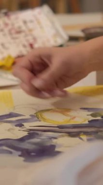 Vertical video. Painting art. Creative process. Talent imagination. Female artist hand creating yellow blue abstract artwork with wax crayon watercolor on canvas.
