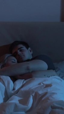 Uyuyan çift. Gece uykusu. Romantik bir ilişki. Aşk uyumu. Barışçıl kadın birlikte uzanıyor, karanlık yatak odasında sarılıyor. Dikey video.