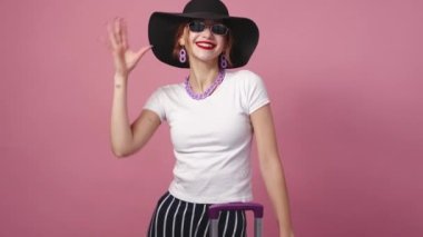 Vacation tour. Happy woman. Inspiration mood. Pretty smiling lady in elegant summer look posing with suitcase on pink background.