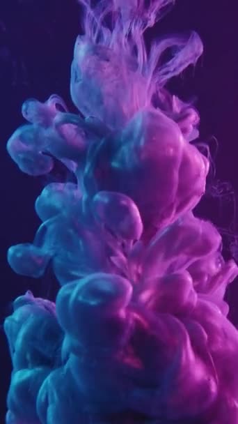 垂直录像 墨水射击 油漆水 染料脱落 蓝色紫色霓虹灯色光液体飞溅烟雾在黑暗抽象的背景下的运动 — 图库视频影像