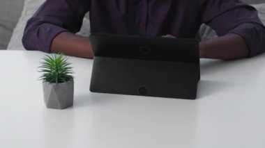 Freelance work. Online business. Internet marketing. Unrecognizable man using tablet working from home on couch at digital office workplace.