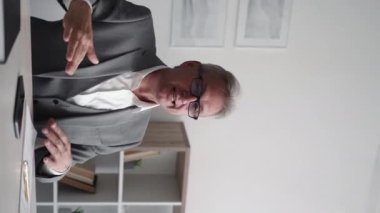 Business consulting. Professional growth. Expertise training. Confident intelligent middle-aged male coach explaining development steps at light modern office interior vertical.