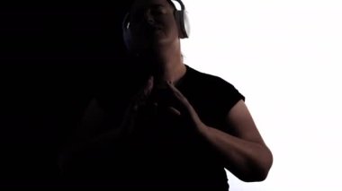 Stereo music. Vibing woman. Silhouette portrait. Excited female listening favorite song dancing in headphones posing divided black white background.