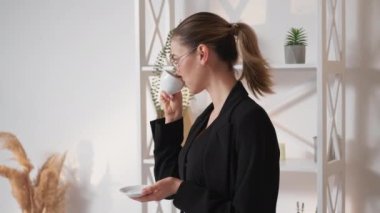 Coffee break. Office woman. Enjoying moment. Smiling elegant lady drinking beverage with satisfaction staying light room interior.