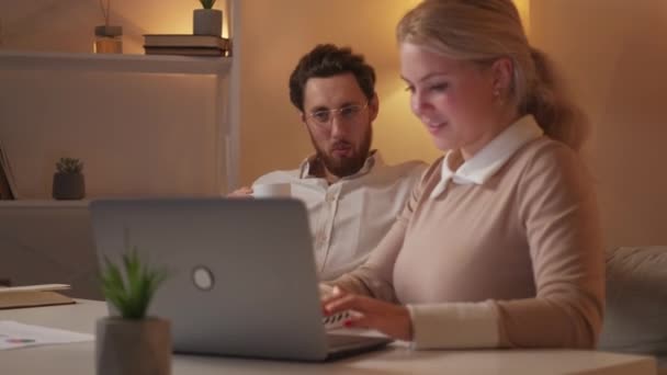 有趣的项目 快乐的同事 迟到了受启发的女人在笔记本电脑上向坐在沙发上的放松男人展示信息 让他们在室内喝咖啡 — 图库视频影像