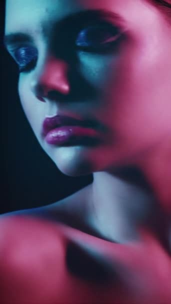 垂直录像 90年代的美女尼昂人的脸迪斯科时尚的样子 淡定少女模特的服装 有艺术妆容 双目紧闭 深红色紫色蓝光闪烁着 — 图库视频影像