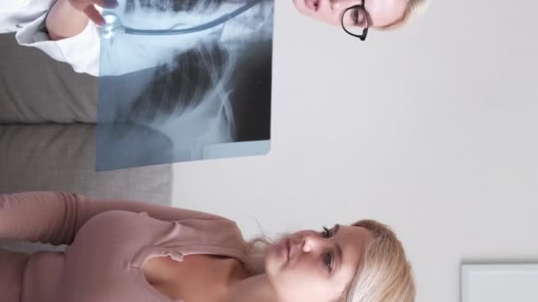 垂直ビデオ 肺熱だ 女性医師 ラボの結果だ X線写真コンサルティング患者を示す医療女性ソファライトオフィス室内に座って — ストック動画