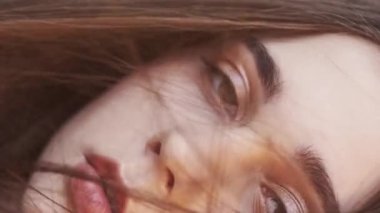 Vertical video. Beautiful woman. Summer time. Sunshine glow. Sensual lady with long hair looking at camera light blur wind blow lens flare slow motion.