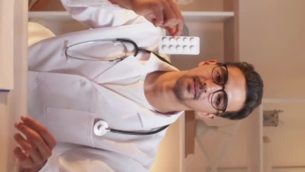 垂直ビデオ 領収書です 男性医師 オンラインサポート スマート男で医療白人でビデオ相談ショー医学用量座って光の部屋のインテリア — ストック動画