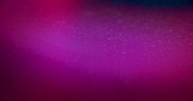 Neon bokeh glow. Blur glitter flare. Glamour shimmering glare. Defocused blue magenta pink color gradient light grain on vibrant abstract background. Shot on RED Cinema camera.