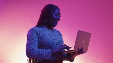 Virtual game. Winning woman. Neon light portrait. Excited female expressing joy looking laptop posing blue purple background.