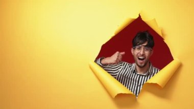 Winner yes. Success celebration. Victory triumph. Excited overjoyed satisfied man showing wow expression in orange breakthrough torn paper hole copy space background.