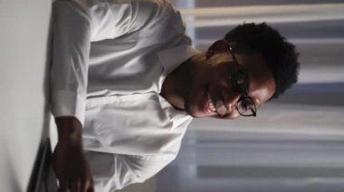 Vertical video. Online job. Freelancer lifestyle. Relaxed cheerful smiling smart business man enjoying late work using laptop at modern home office workplace.