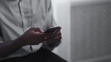 Mobile chat. Gadget people. Online communication. Unrecognizable man hands texting message using phone app on couch at home interior.