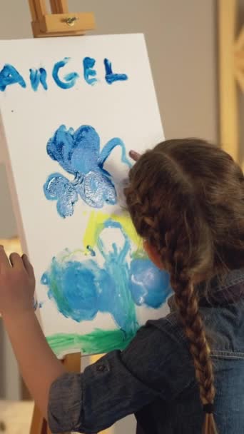 垂直ビデオ 子供アート 創造的な趣味 才能のインスピレーション 小さな女の子の指の絵青黄色天使アートワーク上のイーゼル — ストック動画