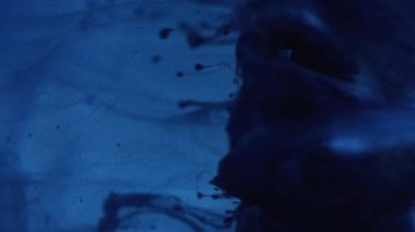 Ink shot. Fluid splash. Smoke cloud. Blue color paint water wave spreading motion over glass cube angle on dark abstract background.