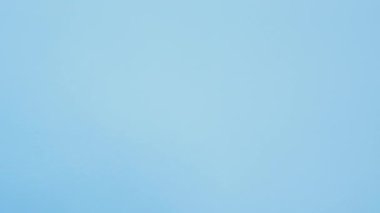 Vertical video. Dislike gesture. Bad idea. Failure shame. Dissatisfied skeptic girl peeking out with disapproval thumbs down on blue background seamless loop.