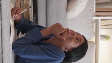Vertical video. Creative writer. Happy woman. Inspiration muse. Dreamy inspired lady making notes in journal laying floor at home.