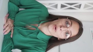 Vertical video. Online interview. Remote conference. Corporate telecommuting. Curious cheerful business woman joining meeting late listening nodding at office workplace.