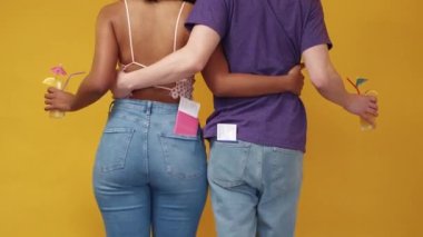 Travel excitement. Dancing couple. Vacation joy. Unrecognizable happy man and woman synchronic moving with passport and tickets in pockets on yellow background.
