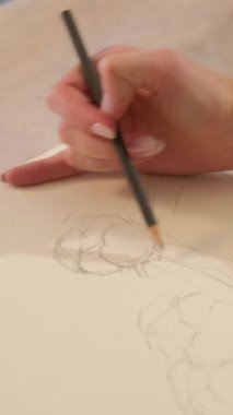 Vertical video. Artwork drawing. Creative process. Painting art. Closeup of female artist hand sketching line with pencil on canvas.