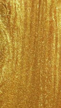 Vertical video. Shiny fluid. Molten gold. Ink flow. Defocused sparkling yellow color bubble glitter texture paint motion abstract background.