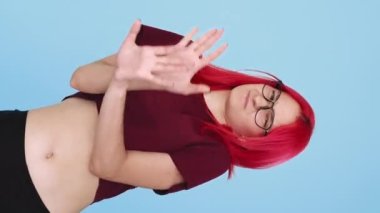 Vertical video. Refusal no. Denial gesture. Rejection protest. Disgust expression. Skeptic girl waving nope on blue background seamless loop.
