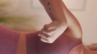 Vertical video. Hands exercise. Sporty woman. Home gym. Unrecognizable lady in sportswear practicing stretching of wrists in light room interior.