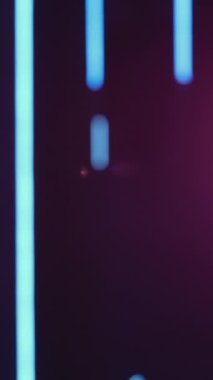 Vertical video. Blur neon light. Lens flare. Bokeh ultraviolet rays. Defocused purple blue color glow lines on dark abstract free space background.