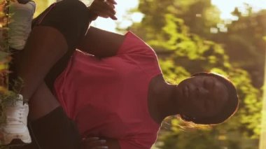 Vertical video. Park meditation. Nature yoga. Outdoor relaxation. Peaceful woman in sportswear performing breathing exercise in lotus position in nature bokeh sunlight.
