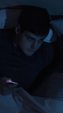 Mobil hile. İnternet ilişkisi. Sadakatsizlik ihaneti. Sadakatsiz sinsi koca gizlice konuşmak için telefonunu kullanıyor. Gece geç saatlerde uyuyan eşiyle yatakta uzanıyor. Dikey video.