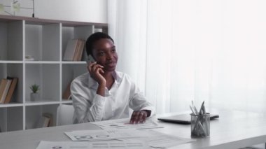 Business phone call. Mobile cooperation. Professional communication. Successful cheerful female leader talking at light home office interior with free space.