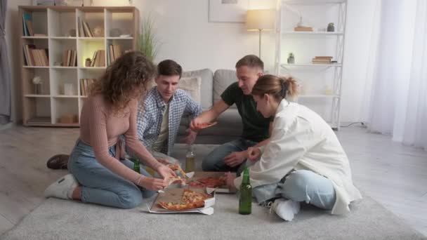 快餐派对 两个日期 生日聚会 快乐的男女朋友们 坐在明亮房间的地板上喝啤酒 吃着美味的披萨 — 图库视频影像