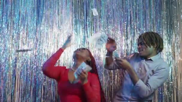金持ちのパーティーだ 興奮したカップル お金を使う 幸せな黒人男性と女性楽しいダンス周り現金ドル上のきらめくカスケードカーテンの背景 — ストック動画