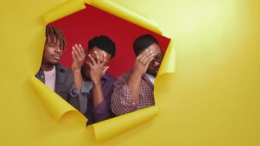 Facepalm gesture. Skeptic black men. Epic fail. Displeased male friends looking from yellow disrupted paper hands on forehead on red background copy space.