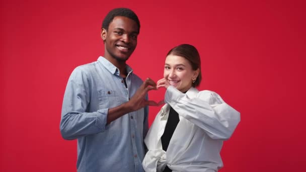爱团结 不同的夫妇 快乐的关系 快乐的欧洲女人和黑人男人心连心手拉手摆出红色的背景 — 图库视频影像
