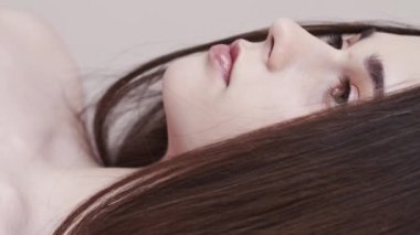 Vertical video. Natural beauty. Sensual woman nude makeup. Smooth care. Perfect skin. Profile of smiling brunette lady with long silky hair posing on neutral.
