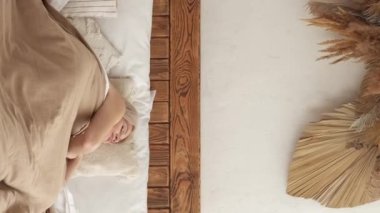 Vertical video. Weekend rest. Sleeping woman. Leisure morning. Calm napping lady enjoying last dream laying comfortable bed in light home interior.